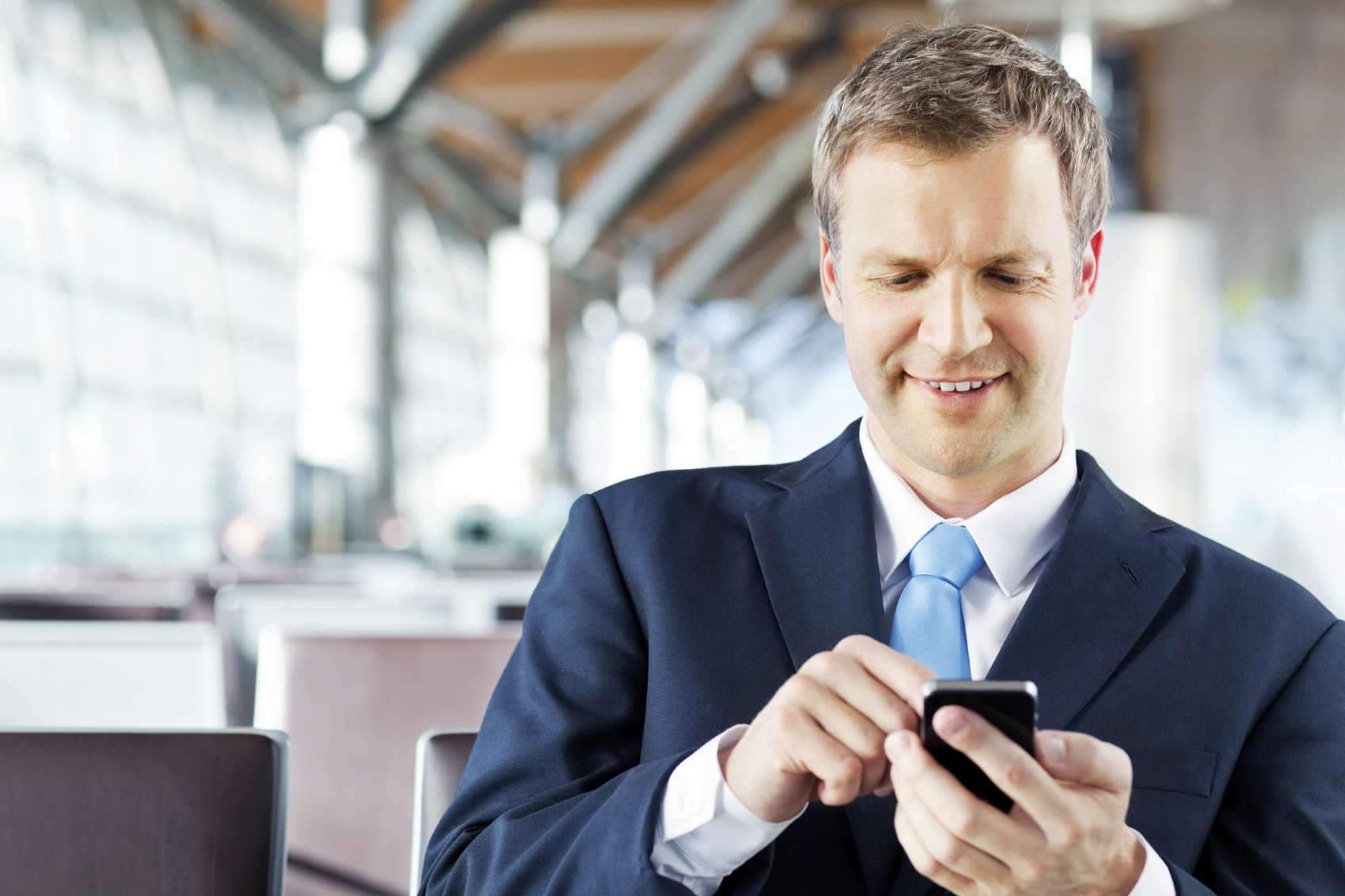 Businessman Writing a Text Message on His Phone At Airport